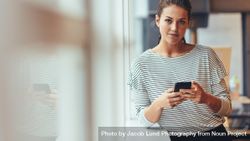 Woman taking break from work standing with cell phone in hand 42wk1b