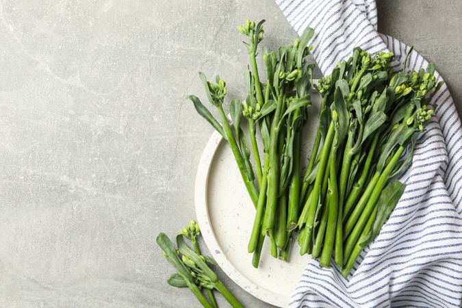 Tray with broccolini and napkin on gray background