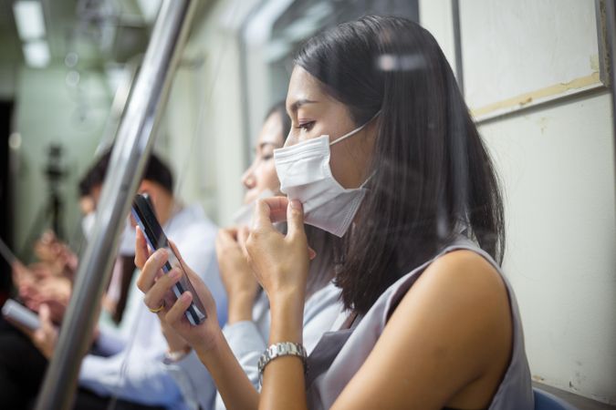 Side view of woman in facemask sitting in subway