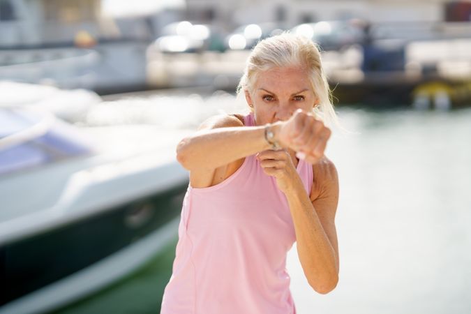 Mature woman practicing punches in a coastal port