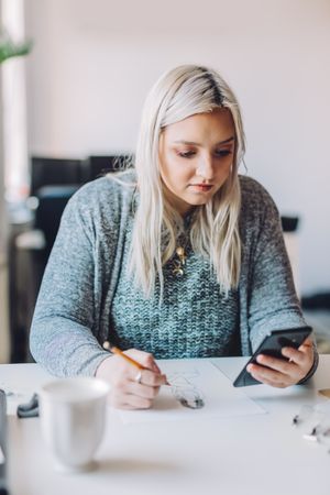 Woman with smartphone doing linearity and first sketches in office