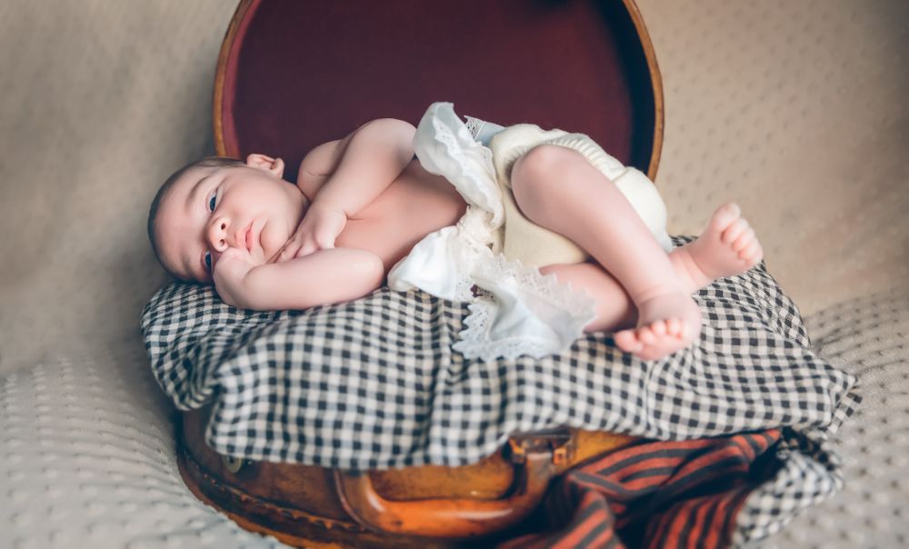 Newborn baby resting lying above of travel suitcase