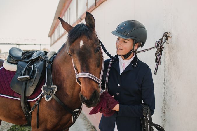 Woman in jockey outfit standing with horse