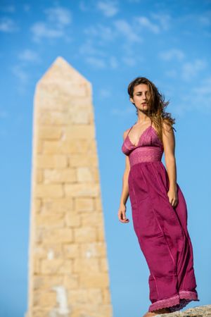 Woman in dress standing near stone monument