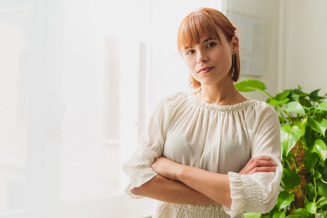 Portrait of a stylish young businesswoman in blouse at her office, with a plant and window in the backdrop