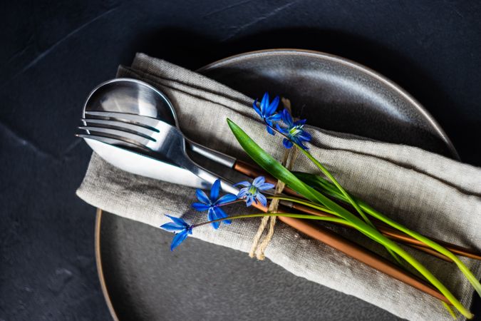 Spring table setting with blue scilla siberica over silverware wrapped in napkin