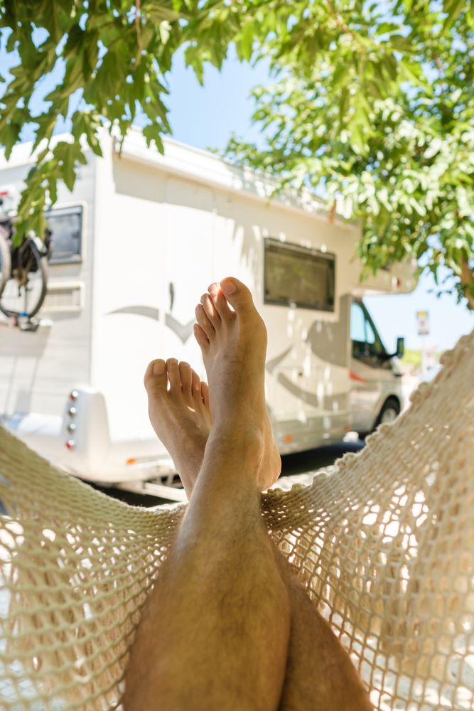 Crop man resting in hammock near RV