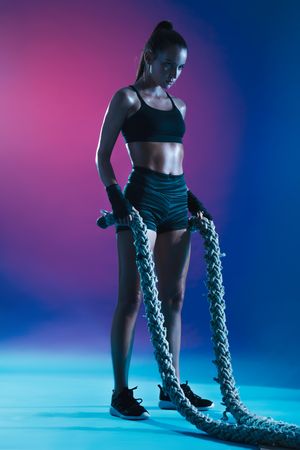 Determined fitness woman holding battle ropes