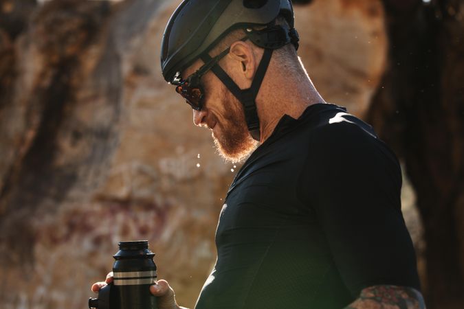 Cyclist making a short break, drinking water to stay hydrated during training