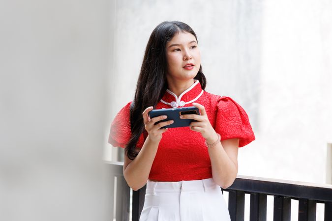 Asian female in Chinese New Year dress chatting on mobile phone