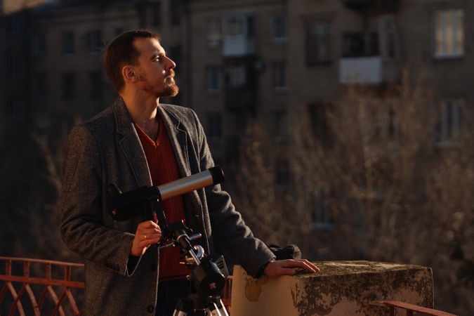 Dedicated skywatcher contemplates solar position using rooftop telescope vantage