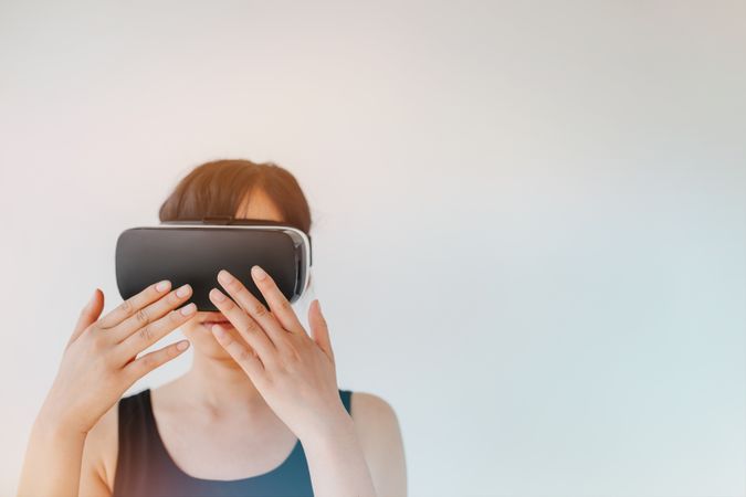 Shot of young woman wearing virtual reality goggle against gray background