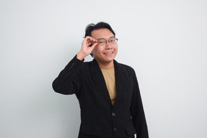 Happy Asian businessman adjusting eyeglasses