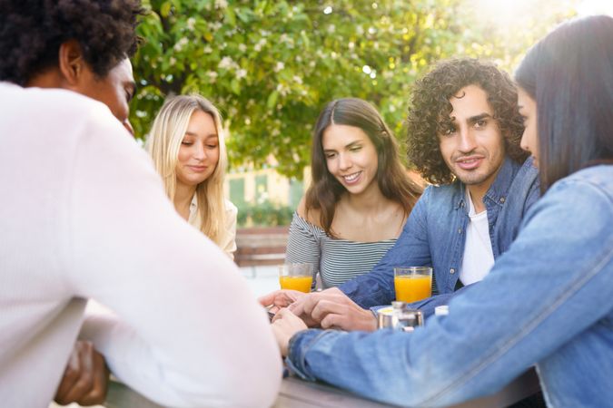 Multi-ethnic group of friends having coffee and juice outside and talking