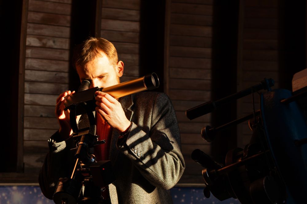 Focused man looks through solar telescope in observatory.