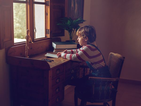 Focused pupil sitting at table and doing homework