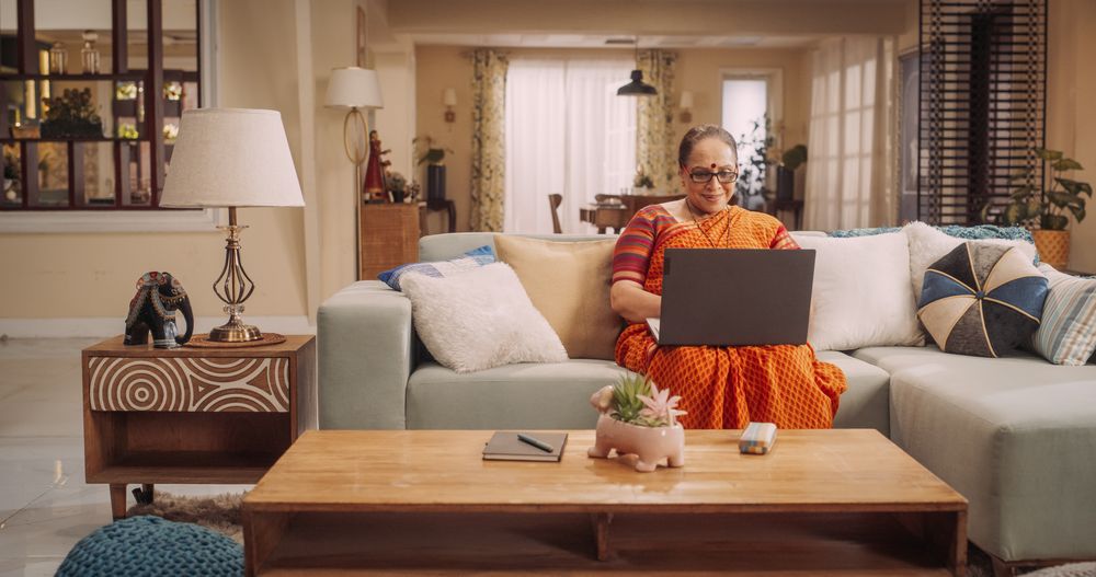 Older Indian Woman Using Laptop at Home: Immersed in Captivating Online Stories, Exploring New Ideas