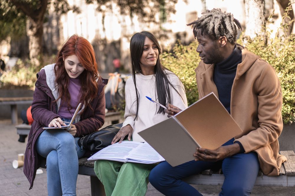 Three students going through their notes outside on campus