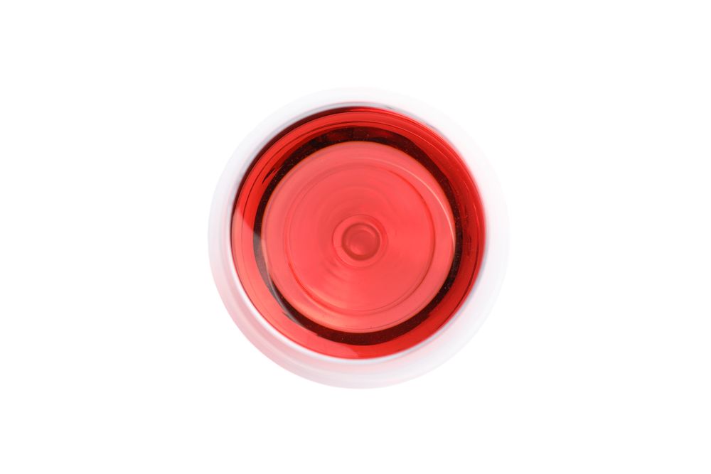 Glass with pink wine isolated on plain background, top view