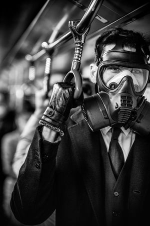 Grayscale photo of person wearing gas mask and suit in train during Hong Kong protests