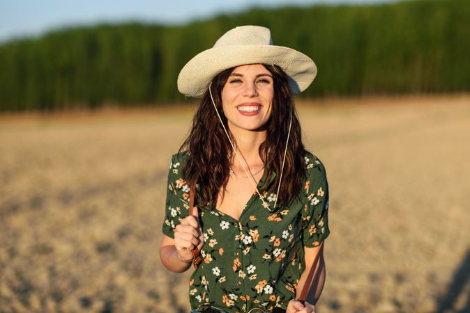 Smiling female in field wearing floral shirt and straw hat