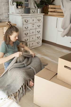 Woman taking out gray blanket from carton boxes