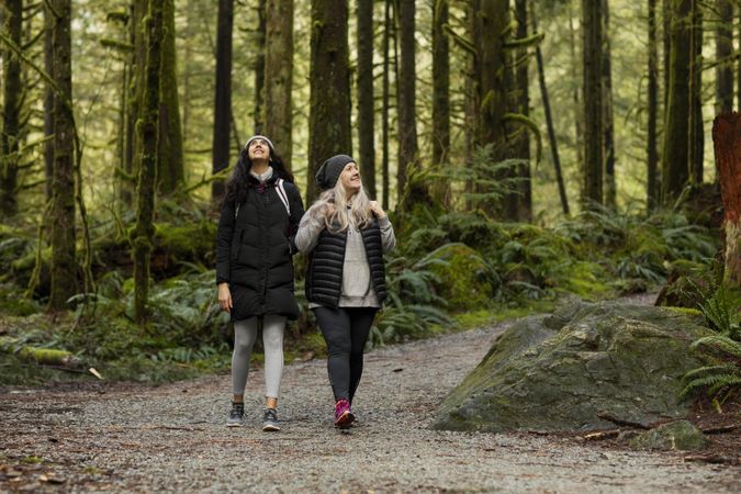 Young female and woman walking on a trail smiling while looking up