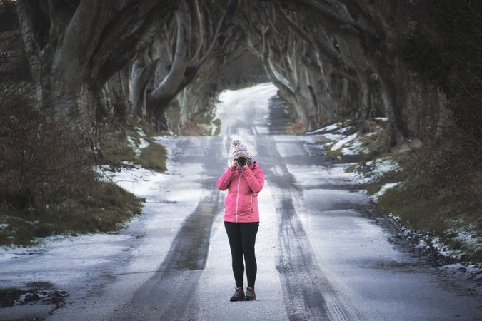 Woman taking photo on beech trees tunnel in winter day in Northern Ireland
