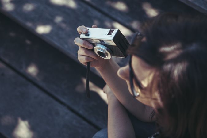 Woman with photo camera sitting and looking along in sunny day