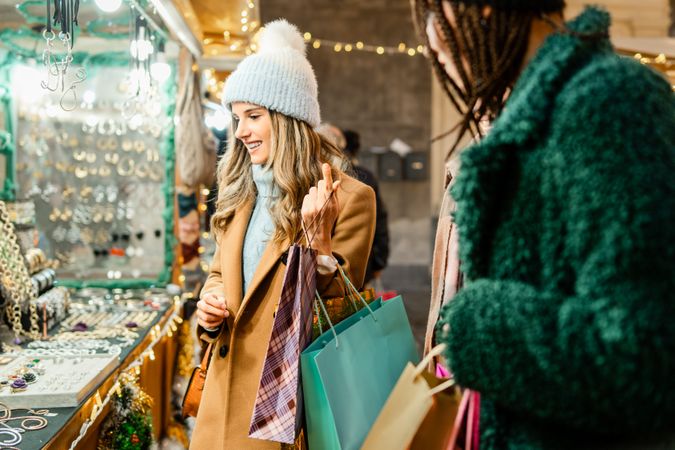 Happy young woman choosing a gift at a Christmas market stall at night.