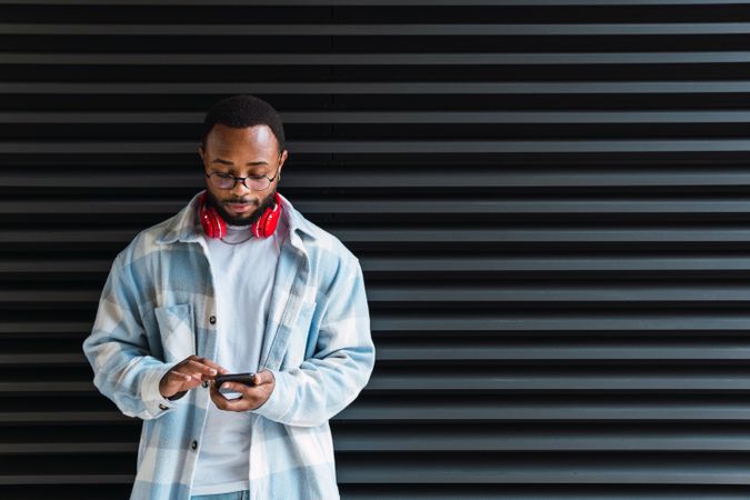 Cheerful Black man with smartphone listening to music