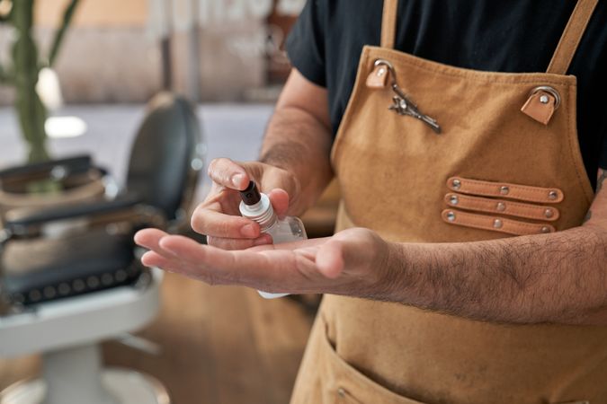 Crop man moisturizing hands with lotion
