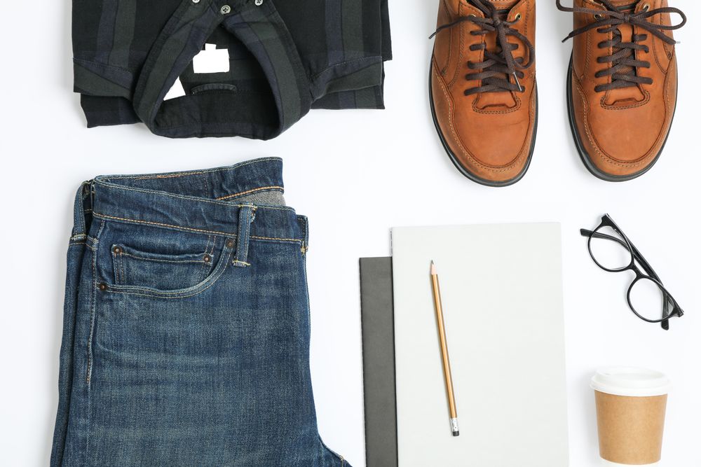 Flat lay composition with shirt, jeans, shoes and glasses on plain background