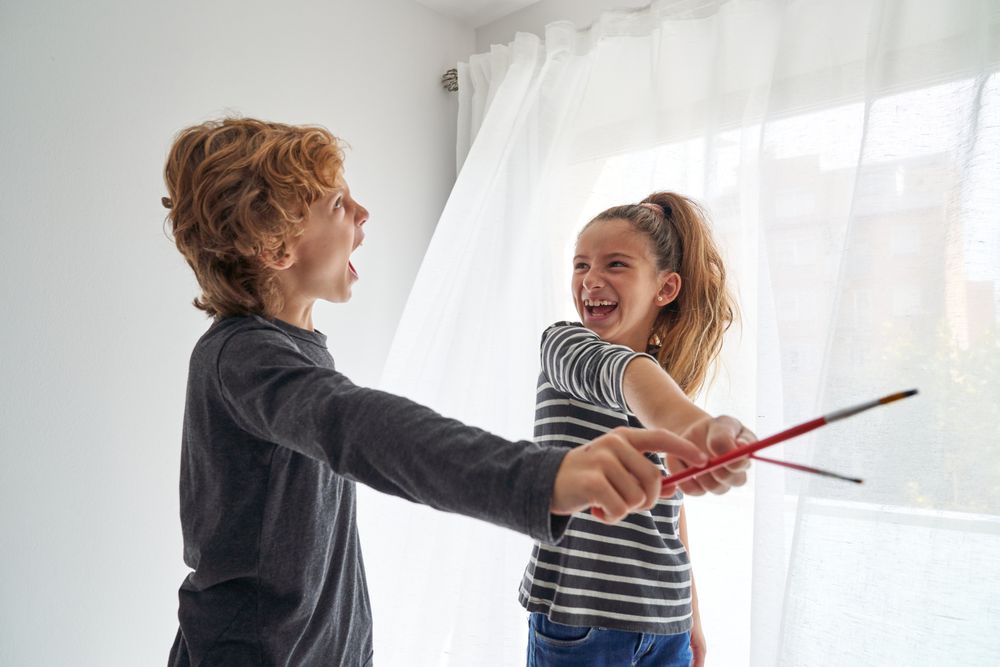 Joyful siblings playing in paintbrushes