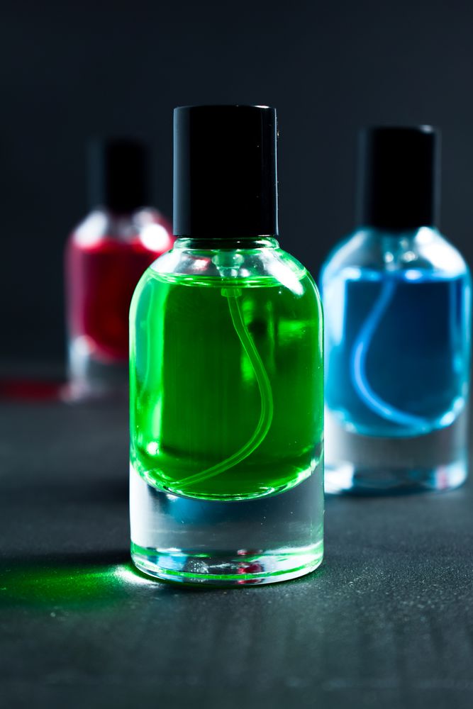 Green, blue and red perfume bottles in dark studio