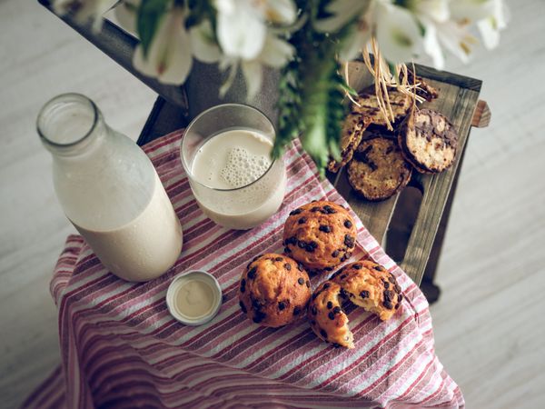 Muffins and biscuits near milk and flowers