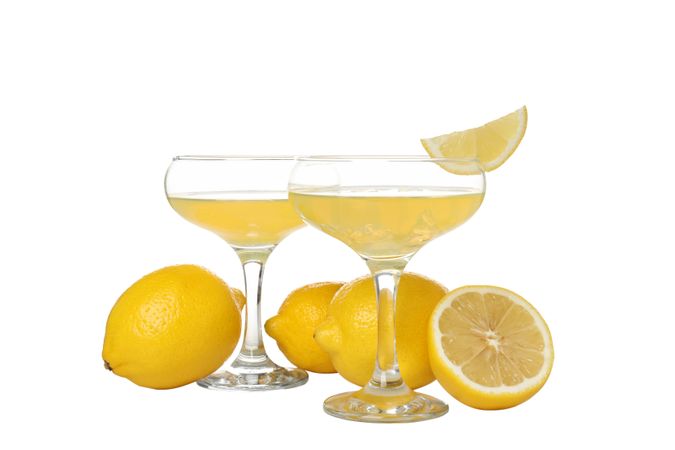 Lemons and cocktail glasses with limoncello, isolated on light background