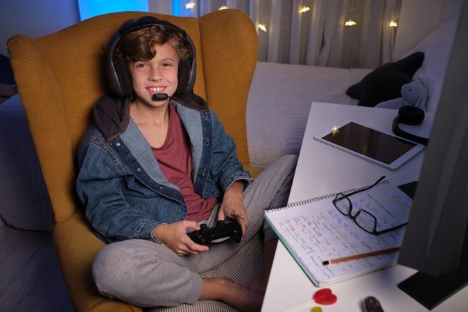 Child in headset enjoying game on computer in dark room