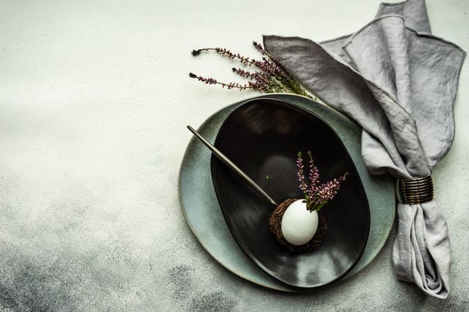 Top view of elegant Easter table with heather and egg decor on dark plate with copy space