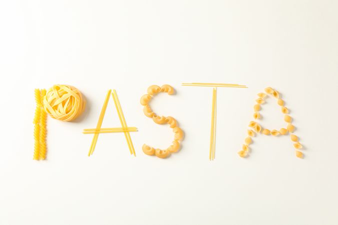 Inscription pasta on light background, space for text. Dry uncooked whole pasta
