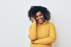 Black woman holding hand to her hair and smiling