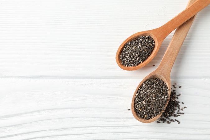 Chia seeds and wooden spoons on wooden background, copy space