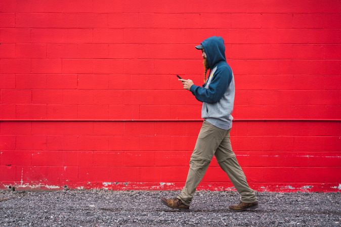 Man using smartphone near red wall