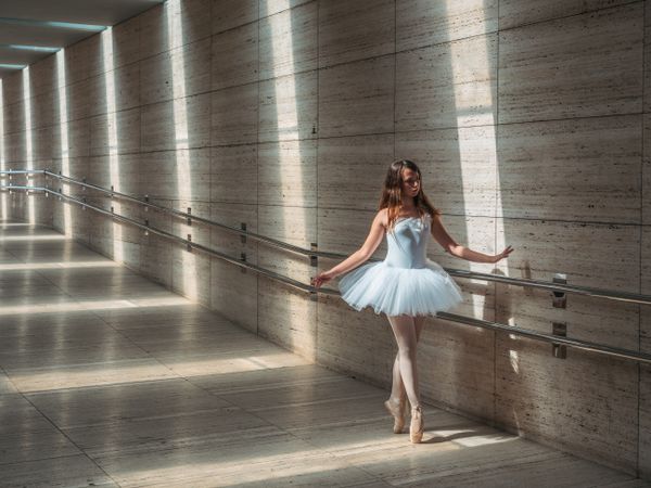 Ballerina doing ballet posing at rail in classroom
