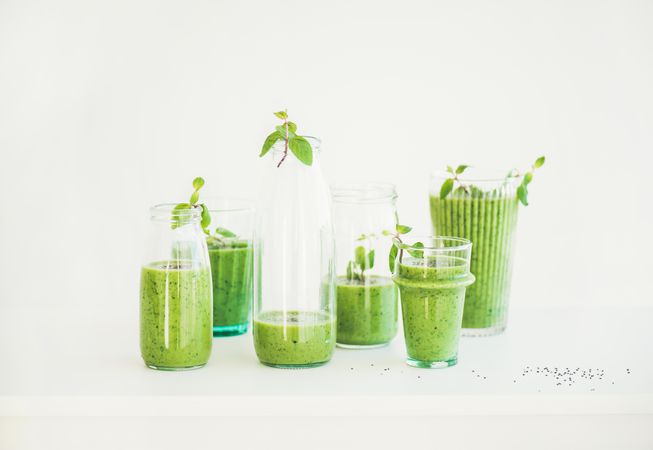 Glass bottles and jars grouped together filled with healthy green juice