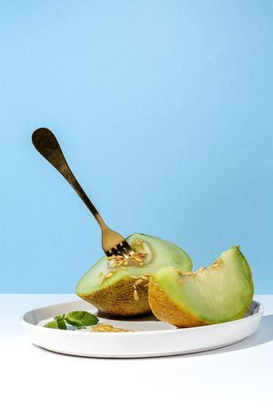 Sliced small melon on plate with spoon and fork
