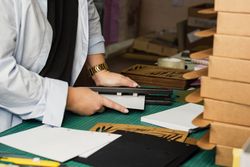 Female hands use hole punch to create perforations in removable paper blocks