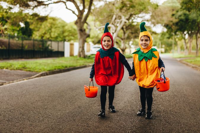 Two little girls in halloween costume trick or treating on the road