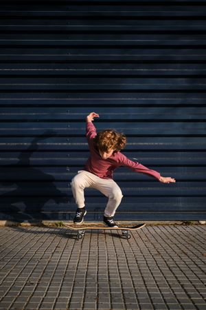 Energetic boy riding skateboard on sidewalk