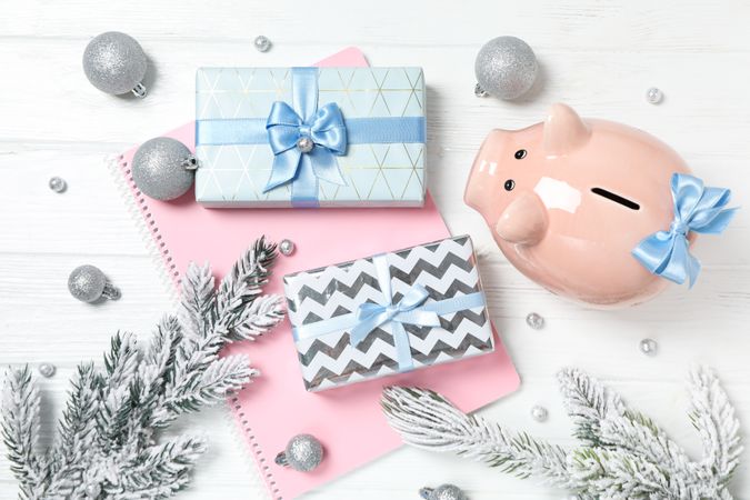 Piggy bank, gift boxes, notepad and fir branches on neutral background, top view